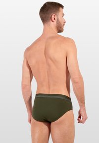 Pánské slipy olivově zelené barvy s jednobarevným designem, měkkou texturou a kontrastním páskem s logem značky. Střižené pro těsné přilnutí.