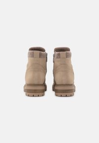 Beige Knöchelstiefel aus glattem Wildledermaterial, mit geripptem Kragen und einer leicht robusten Sohle mit sichtbaren Profilmustern.