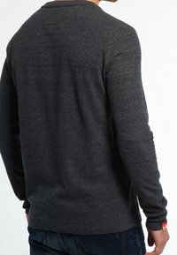 Pitkähihaisen pyöreäkauluksisen paidan tummanharmaa väri, pehmeä materiaali, yksinkertainen design ja etiketti alapuolella.