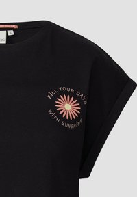 Zwarte T-shirt van zacht materiaal, met een ronde hals en korte mouwen. Versierd met een roze bloemenafbeelding en tekst.