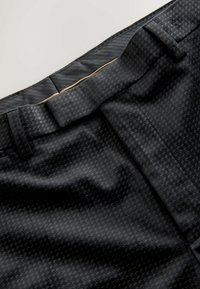 Black pants featuring a textured pattern of small crossing lines, a flat waistband with belt loops, and a smooth fabric finish.