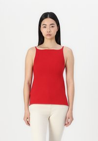 Débardeur rouge côtelé avec fines bretelles, présentant une silhouette ajustée et des fentes sur les côtés. Fabriqué en tissu doux et extensible pour plus de confort.