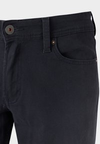 Dunkelblaue Hose aus Baumwollmischgewebe mit Knopf- und Reißverschluss, vordere Tasche mit Nahtdetail und subtiler Textur.