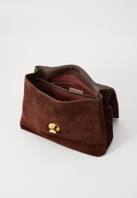 Pochette en suède marron avec une surface texturée, grande fermeture magnétique et un intérieur bordeaux contrastant doté d'une poche zippée intérieure.