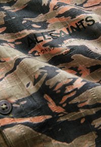 Kamikaze raštas su juodos, smėlio ir koralinės spalvos atspalviais. Jame yra užrašas "ALLSAINTS" ir mygtuko detalė.