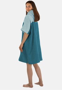 Türkises Badetuchkleid aus Frottee mit einem hellblauen Kragen, kurzen Ärmeln und seitlichen Schlitzen, ausgestattet mit einem lässigen Schnitt und einer Kapuze.