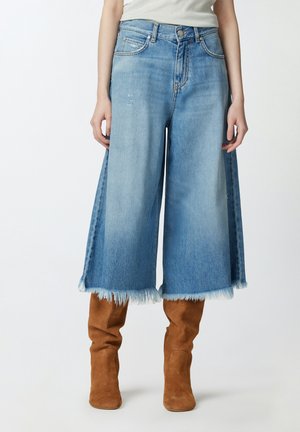 Culotte in denim azzurro chiaro con orlo sfrangiato e vestibilità ampia e morbida. Abbinati a stivali marroni fino al ginocchio. Presenta un classico design a cinque tasche.
