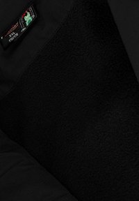 Černá bunda s fleecovou podšívkou a hladkým vnějším materiálem. Obsahuje štítek s kreslenou žábou a velikostí "XXL."