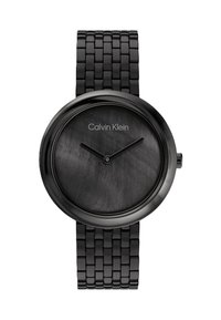 Črno metalno uro z okroglo fasado, teksturiranim črnim številčnico, minimalnimi oznakami in povezanim zapestjem. Opremljena je z logotipom Calvin Klein.