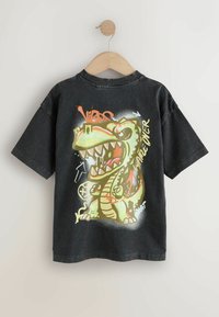 Czarny t-shirt z krótkim rękawem z grafiką zielonego dinozaura z wyolbrzymionymi cechami, towarzyszącym kolorowym napisem i dodatkowymi detalami.