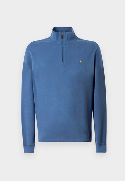 Μπλε πουλόβερ φούτερ με μισό φερμουάρ στον γιακά, ραμμένα μανίκια και ένα μικρό κεντητό λογότυπο στο στήθος. Φτιαγμένο από μαλακό ύφασμα με λεία υφή.