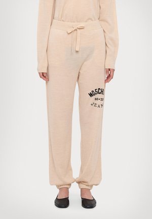 Beige Sweatpants mit einem Kordelzugbund, umschlagvollen Knöcheln und schwarzem gesticktem "MOSCHINO Jeans"-Logo an der Seite. Weiche Stofftextur.