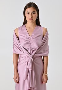 Abito senza maniche di un rosa chiaro con busto arricciato, scialle drappeggiato legato in vita e texture di satin liscia. Presenta un bottone rotondo come punto di accento.