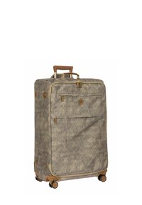 Valise à roulettes en tissu beige texturé avec des accents marron, dotée de deux poches avant et d'une poignée rétractable pour un transport facile.