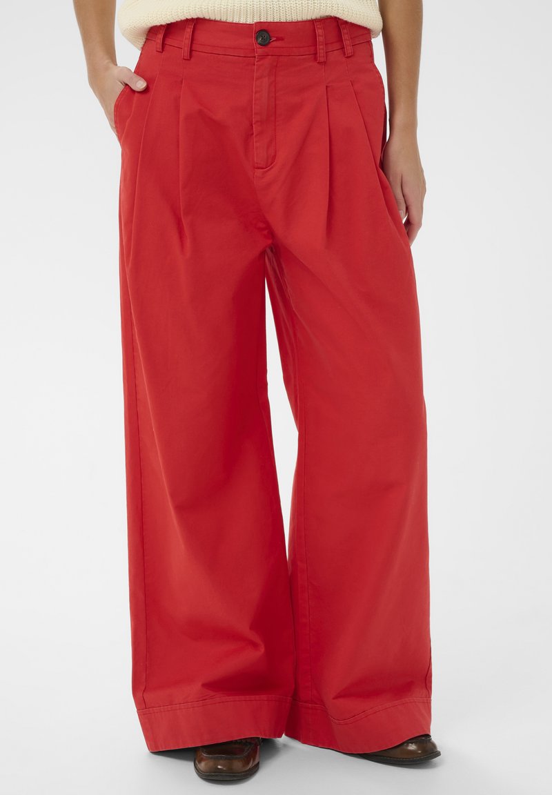 Hlače širokih nogavica od jarko crvene pamuka, s prednjim naborima, bočnim džepovima, kopčanjem na gumbe i glatkom teksturom.