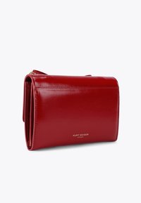 Portafoglio in pelle rossa con una texture liscia, dotato di chiusura con zip e logo dorato. Design compatto con forma rettangolare e bordi ripiegati.