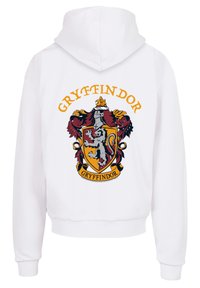 Sudadera blanca con un diseño del emblema de Gryffindor en rojo, dorado y negro, que incluye un león, armadura y el texto "GRYFFINDOR" arriba. Tela suave, corte oversize.