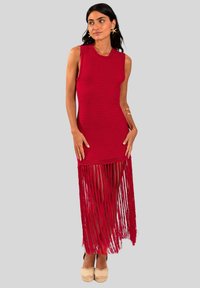 El vestido maxi de ganchillo rojo presenta un corsé ajustado y un dobladillo largo con flecos. La textura es de punto, con un diseño sin mangas y una silueta recta.