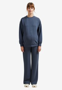 Dunkelblaues, übergroßes Sweatshirt mit langen Ärmeln, gerippten Bündchen und passenden, lockeren Hosen, aus weichem Stoff, entworfen für Komfort.