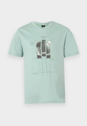 Lys turkis T-skjorte med korte ermer og et frontmotiv som viser en svart-hvitt bildesign og tekniske linjetegninger.