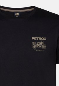 Camiseta de algodón negra con cuello redondo, que presenta un gráfico dorado de una motocicleta y el texto "PETROL" en el frente.