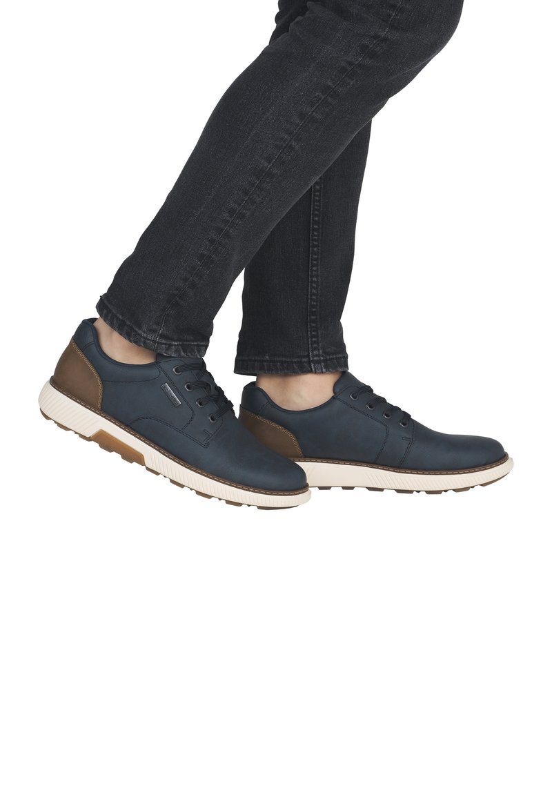 Zapatillas sintéticas azul marino con detalles en marrón, con diseño de cordones, suela de goma texturizada y media suela blanca en contraste.