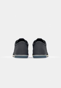 Mørkegrå sneakers med en glat, mat overflade, rund tå og kontrastfuld lys gummisål. Hæløje for nem påtagning.