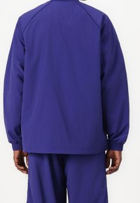 Lila lättviktsjacka med elastiska ärmslut och avslappnad passform. Har en enkel design utan dekorationer, lämplig för avslappnad användning.