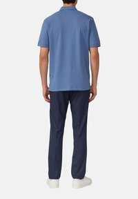 Helles blaues Poloshirt mit kurzen Ä sleeves aus weichem Baumwollmaterial, mit einem flachen Kragen, kombiniert mit marineblauen Hosen und weißen Sneakern.