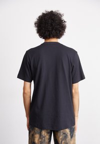 Μαύρη βαμβακερή μπλούζα με κοντά μανίκια, στρογγυλή λαιμόκοψη και ευθεία γραμμή. Διαθέτει απλό σχέδιο, ελαφριά υφή και λεία επιφάνεια.