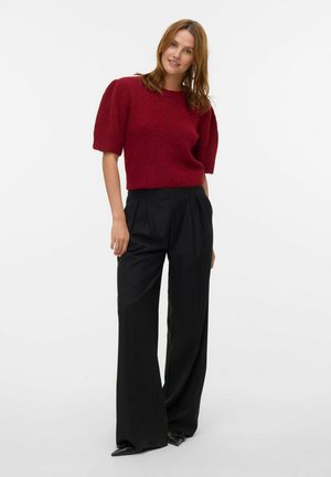 Bordeaux gebreide trui met korte pofmouwen en zwarte wijde broek. Zachte textuur met een cropped ontwerp. Hakken maken de look compleet.