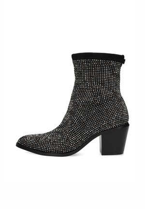 Black ankle boot with a fitted ribbed upper, covered in metal studs, and a chunky heel. Features a pointed toe and sleek silhouette.