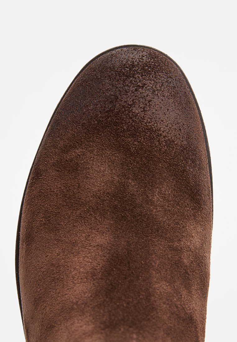 Stivale alla caviglia in suede marrone con una finitura liscia e texture, punta arrotondata e suola piatta. Design senza cuciture e aspetto minimalista.