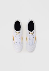 White athletic shoes with gold accents, lace-up design, textured paneling, and cushioned black interior. Brand logo prominently displayed.