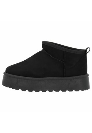 Bottine noire à la cheville avec semelle épaisse, design slip-on, matière supérieure douce et languette à l’arrière, vue de côté.