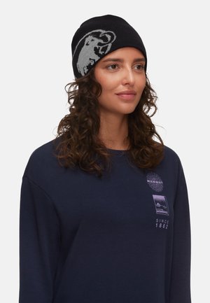 Black knit beanie with a grey animal logo, paired with a navy long-sleeve shirt featuring a brand logo and two small mountain graphics.