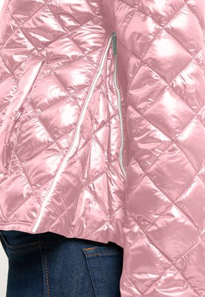 Pink quilted jacket with diagonal stitching and an open vertical zipper, worn over blue denim jeans.