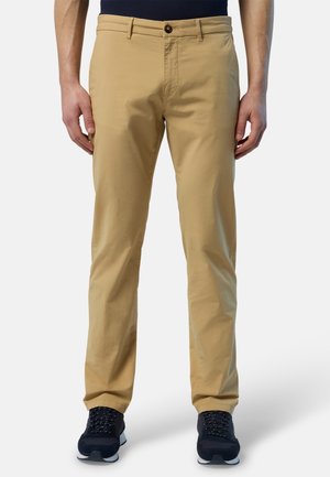 Chino in cotone beige con vestibilità dritta, dotati di chiusura con bottone e tasche laterali. Abbinati a sneakers scure per un contrasto.