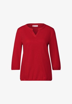 Haut rouge avec un col en V et des manches trois-quarts. Tissu doux avec une texture lisse et sans motifs ni accents visibles. Coupe décontractée.