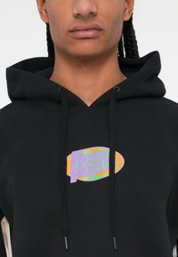 Sudadera negra con capucha que presenta un colorido logo ovalado que dice "Rivivia Project". La tela es suave y tiene detalles de cordones.
