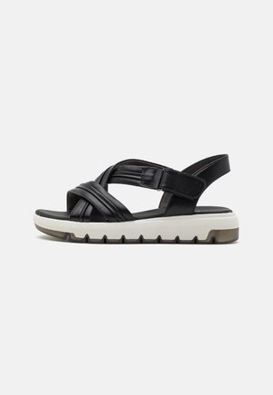 Black leather sandals with crossed straps, adjustable ankle strap, cushioned sole, and textured white midsole with grooves.