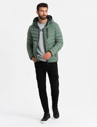 Vadderad grön jacka med huva, dragkedjefickor och en grå sweatshirt under. Bärs med svarta cargobyxor och svarta sneakers.