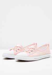 Zapatillas de lona rosa con punta y suela de goma blanca, que presentan ojetes de metal y un diseño de cordones, textura suave y una sutil franja lateral.