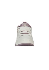 Zapatilla blanca con acentos morados, parte superior texturizada, cierre de cordones, cuello acolchado y detalle del logo en la lengüeta. Suela de goma con tracción.