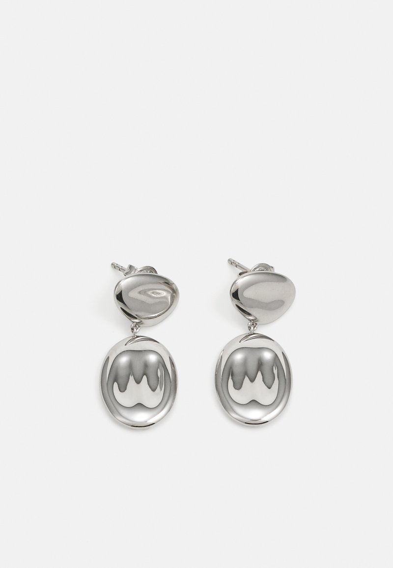 Brincos em prata com um topo arredondado e polido, e um pendente circular e refletivo com um padrão ondulado.