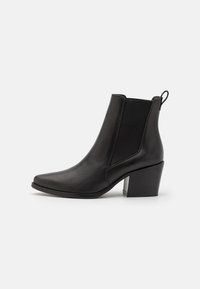 Černá kožená kotníková bota s špičatou špičkou, elastickými bočními panely a texturovaným blokovým podpatkem. Minimalistický design, hladký povrch.