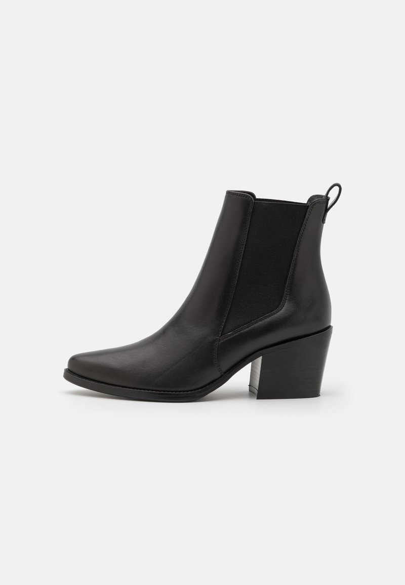 Černá kožená kotníková bota s špičatou špičkou, elastickými bočními panely a texturovaným blokovým podpatkem. Minimalistický design, hladký povrch.