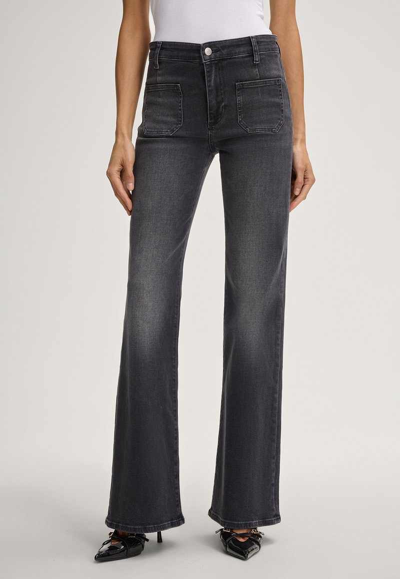 Hoge taille, zwarte denim flare jeans met voorzakken, vervaagde textuur en een recht beenontwerp, gecombineerd met puntige zwarte schoenen.