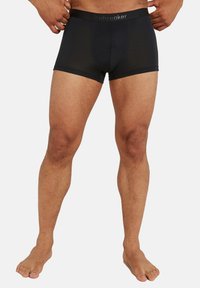 Černé boxerky vyrobené z hladké látky, s elastickým pasem s logem a přiléhavým střihem, který sahá po střední stehna.