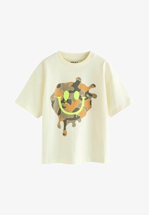 Crème-kleurig T-shirt met een losse pasvorm. Bevat een camouflage smiley-gezicht ontwerp in tinten groen en bruin, met druppel-effecten.